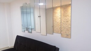 A room with a black sofa, a wall-mounted mirror, and a textured wall. - Near the main park of Salento (Salento)