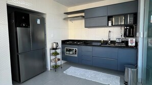 Una cocina moderna con un refrigerador de acero inoxidable, estufa a gas y una cafetera.