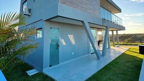 Una casa moderna de dos pisos con techo plano, ventanas amplias y un balcón.