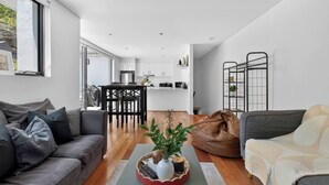 A modern living space with a grey sofa, a bean bag, and a coffee table with a plant. - Northern Breeze Terrace Haven near Curl Curl Beach (Brookvale)