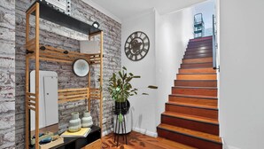 A modern interior with a wooden staircase, a large mirror, and a potted plant. - Northern Breeze Terrace Haven near Curl Curl Beach (Brookvale)