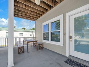 Une véranda abritée avec une table et des chaises, une porte-fenêtre coulissante et une vue sur la maison voisine.