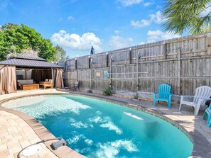 Un jardin avec une piscine, une terrasse en bois et un espace salon extérieur.