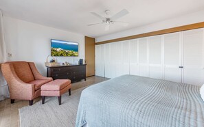 Ein Schlafzimmer mit Bett, Sessel, Kommode, Fernseher und Kleiderschrank.