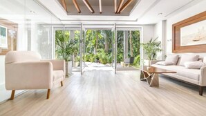 A modern living room with a glass door leading to a balcony, a sofa, a coffee table, and a minimalist ceiling design. - Beautiful view and location, roof terrace with sea view! (Playa del Carmen)