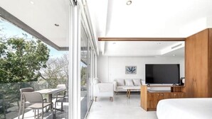 A modern bedroom with a large bed, a TV, and a sofa. There is a balcony with a table and chairs. - Beautiful view and location, roof terrace with sea view! (Playa del Carmen)