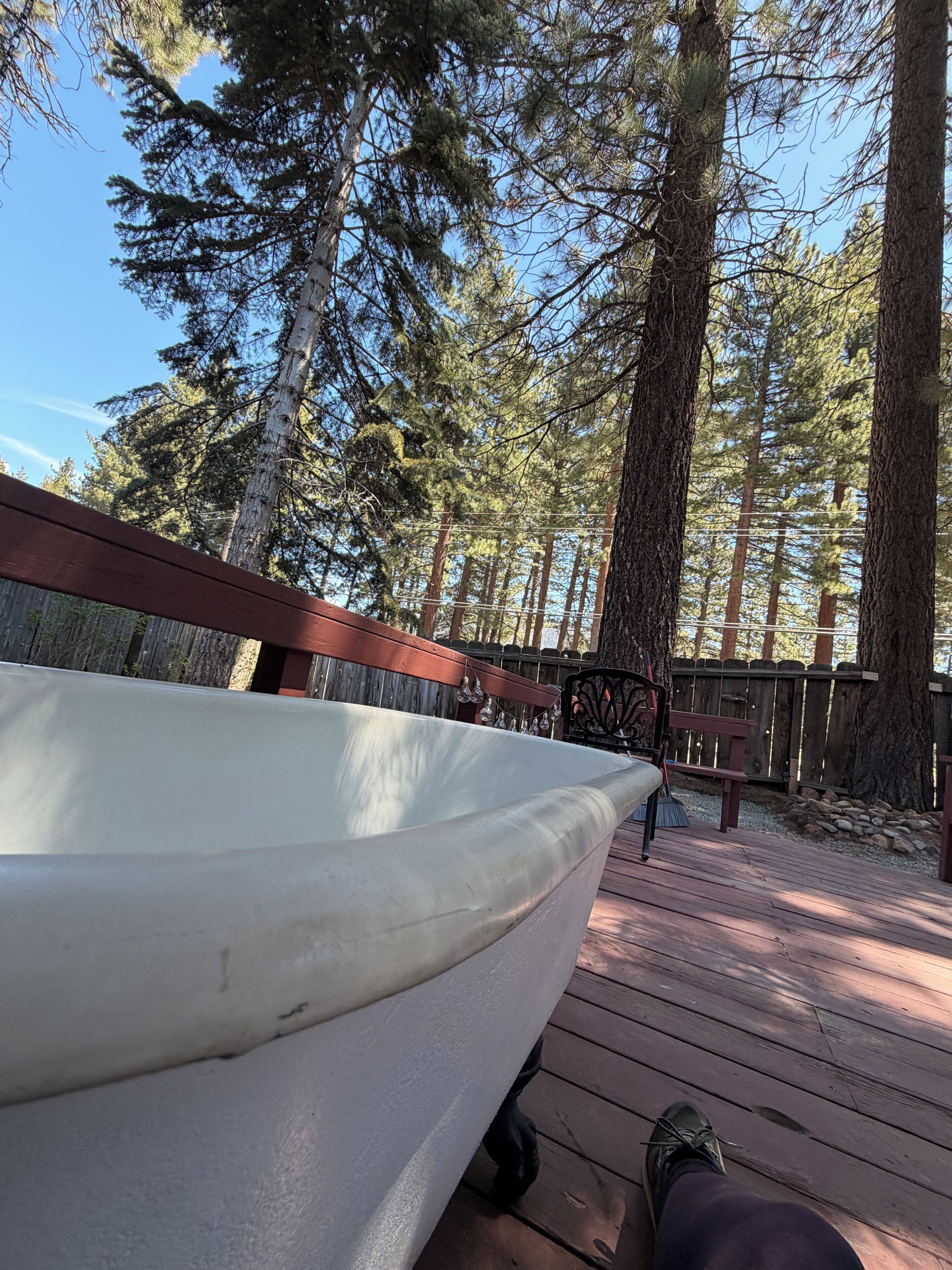 Eine Holzterrasse mit einem Boot, umgeben von hohen Bäumen.