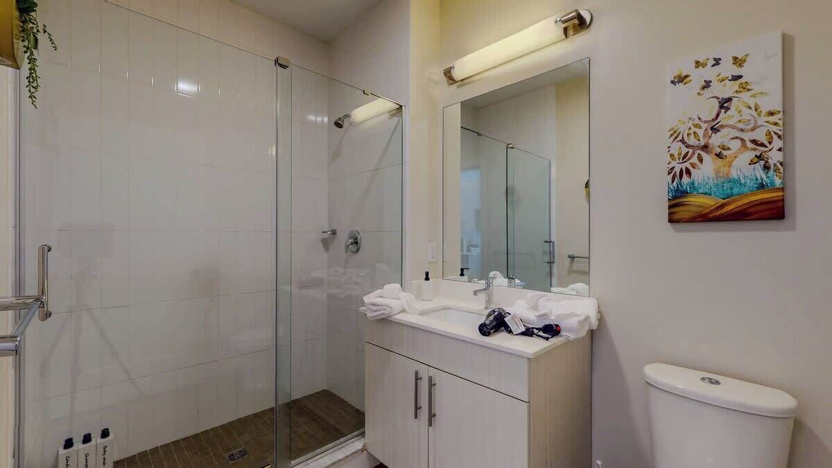 Ein modernes Badezimmer mit Duschkabine aus Glas, einem Waschtisch mit Spiegel und einer Toilette.