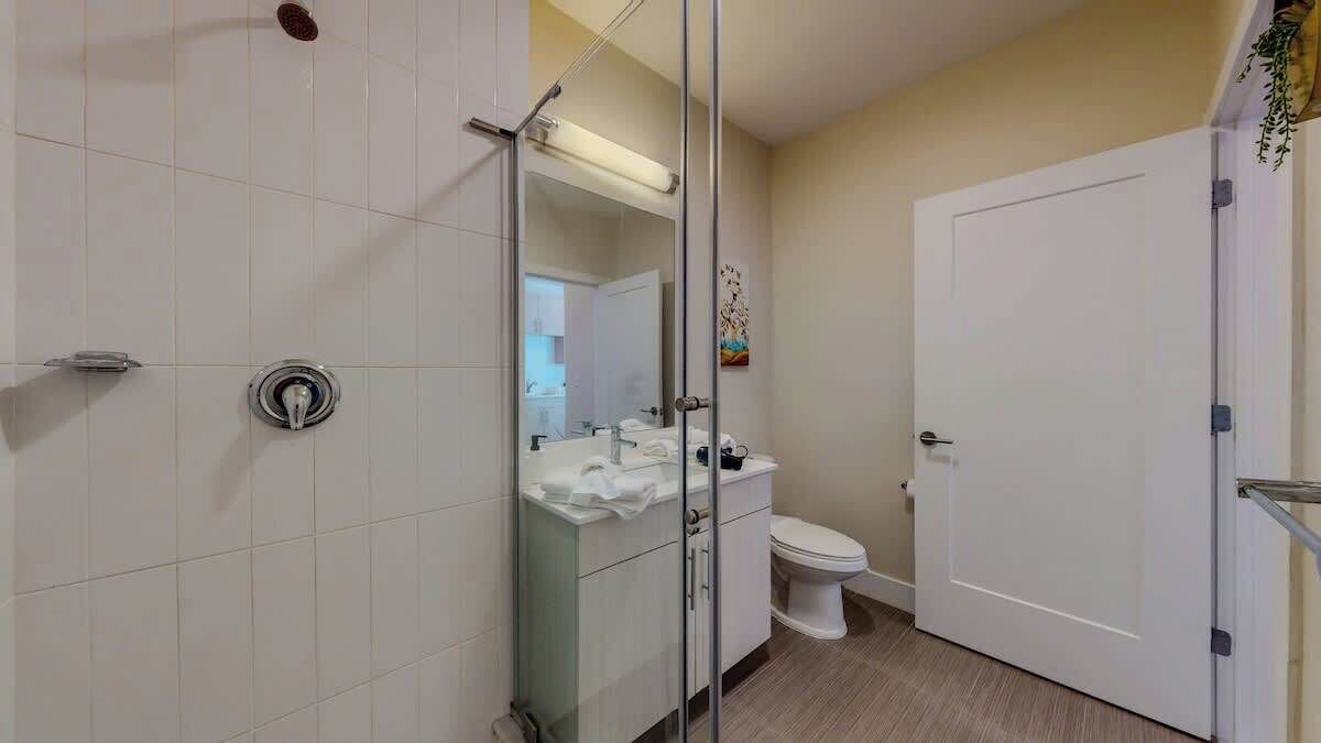 Een badkamer met douche, toilet en wastafel.