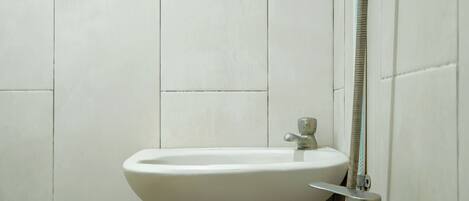 Ein Badezimmer mit Waschbecken, Wasserhahn und Duschschlauch.