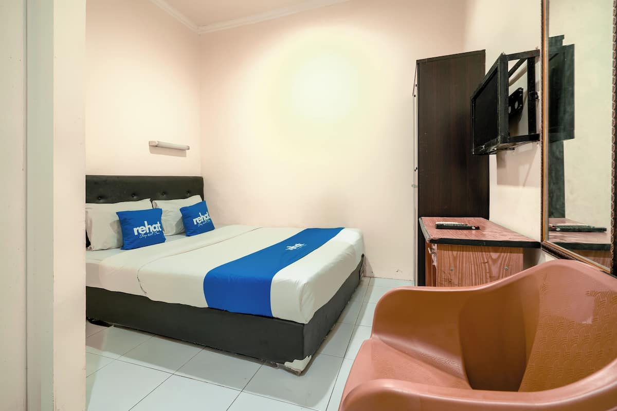 Une chambre d’hôtel avec un lit, une chaise, un bureau et un téléviseur.