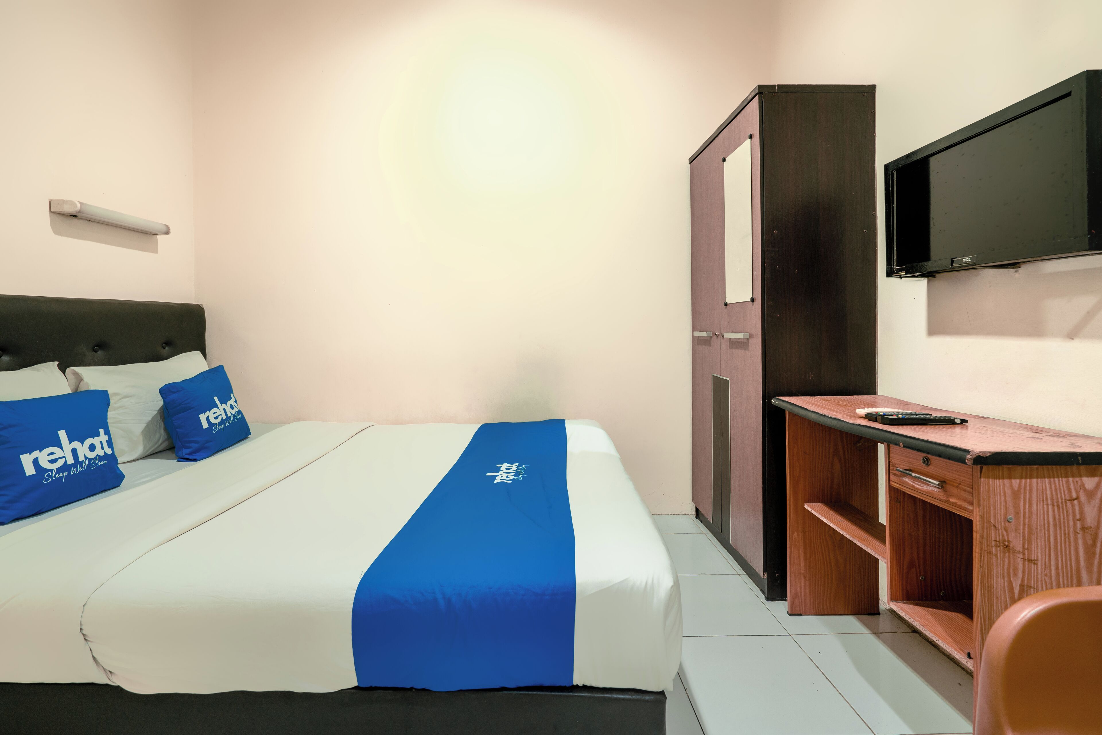 A hotel room with a bed, a desk, a chair, a television, and a wardrobe.