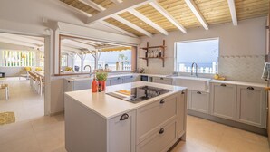 Eine moderne Küche mit Kochinsel, weißen Schränken und Meerblick.