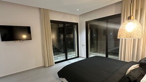 Ein modernes Schlafzimmer mit einem großen Bett, einem Flachbildfernseher und großen Fenstern.