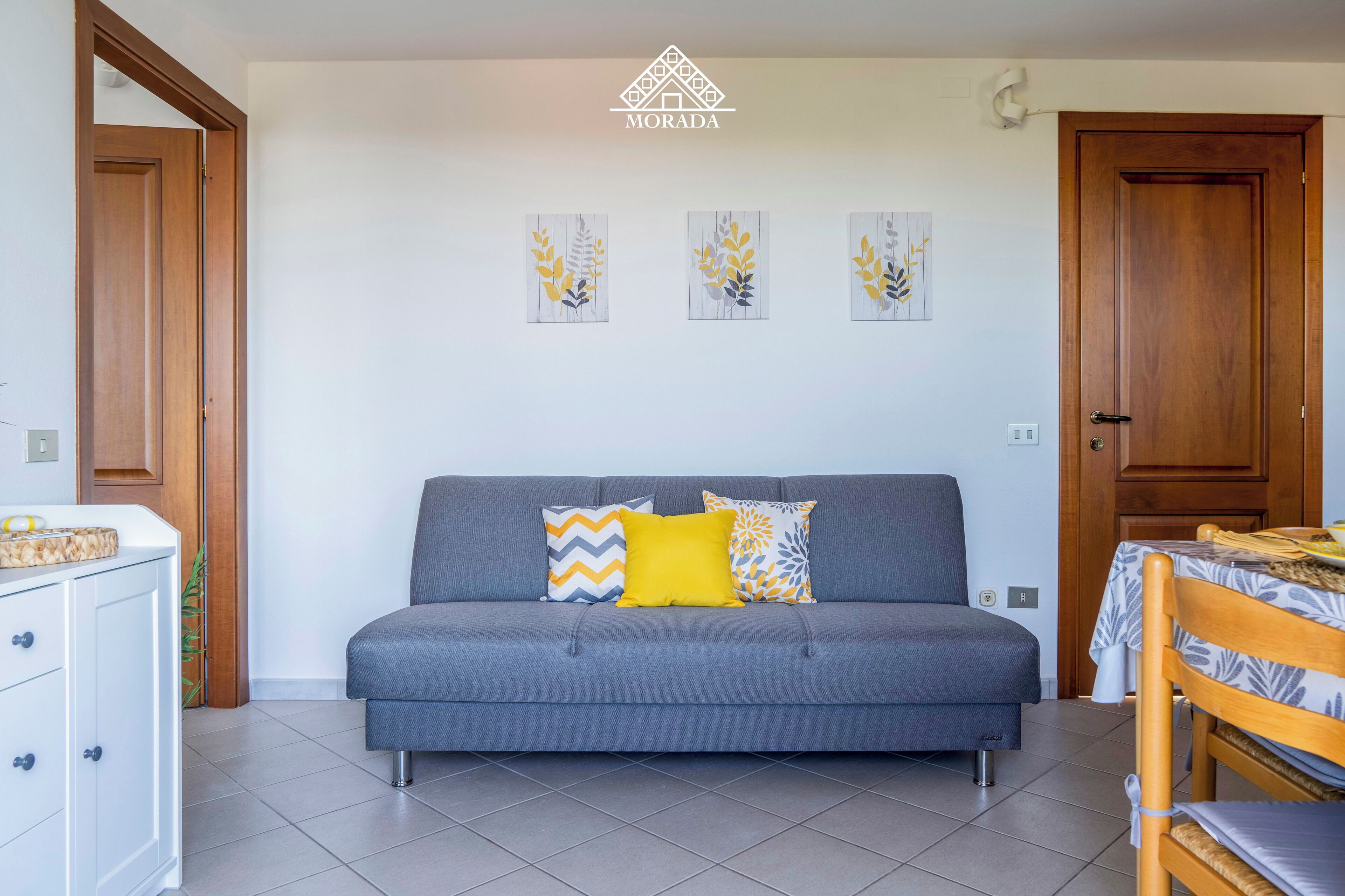 Una sala moderna con un sofá gris, una mesa de comedor de madera y un mueble blanco.