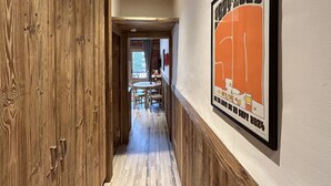 A wooden hallway with a dining area in the background. - Chalet de Solaise B03 (Val-d'Isère)