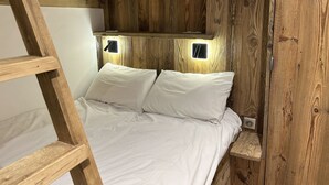 A bunk bed with white bedding and two wall-mounted lights. - Chalet de Solaise B03 (Val-d'Isère)