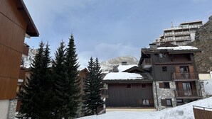 A multi-story building with a stone facade, wooden balconies, and a snow-covered roof. - Chalet de Solaise B03 (Val-d'Isère)