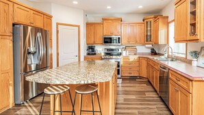 A modern kitchen with wooden cabinets, stainless steel appliances, and a granite countertop. - 5BR I Sleeps 10, King x2, Pack n Play, Air Hockey (Fargo)