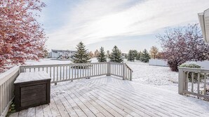 A wooden deck with a railing, snow-covered ground, and trees in the background. - 5BR I Sleeps 10, King x2, Pack n Play, Air Hockey (Fargo)