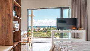 Ein Schlafzimmer mit großem Fenster, einem Bett, einem Fernseher und einem Holzregal.