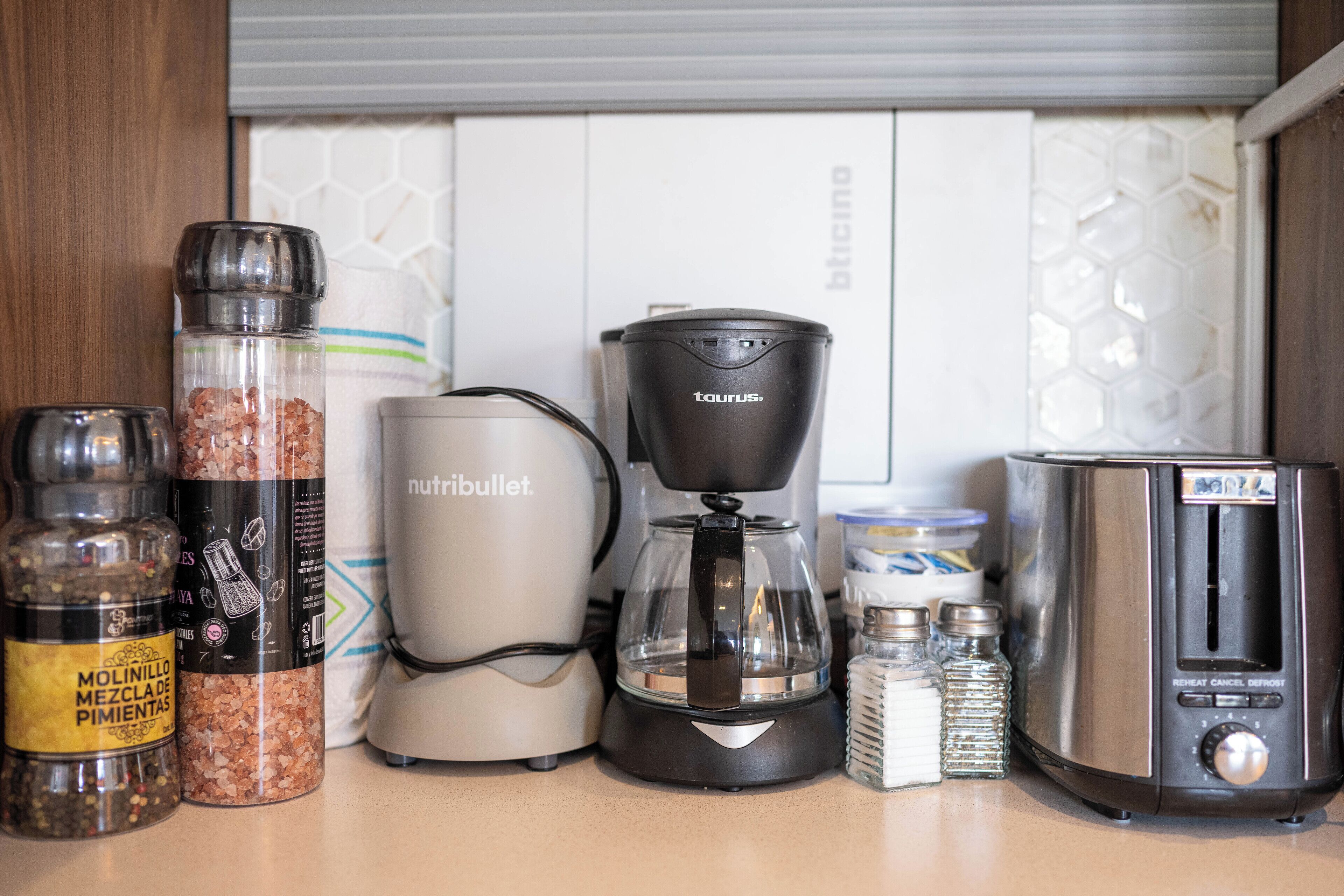 Una encimera de cocina con cafetera, tostadora y varios recipientes de especias.