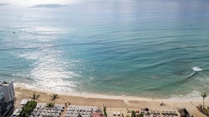 Ein Strand mit klarem türkisblauem Wasser, einem Sandstrand und Sonnenschirmen.