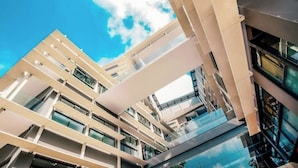Ein modernes, mehrstöckiges Gebäude mit Glasfassade und blauem Himmel.