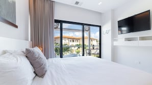 Ein modernes Hotelzimmer mit einem großen Bett, einem Flachbildfernseher und einem Balkon mit Blick auf Gebäude.