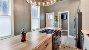 A modern kitchen with a wooden countertop, a gas stove, a built-in oven, and a stainless steel refrigerator. - Large Milwaukee Home 4BR Fast Wifi (Milwaukee)