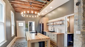 A modern kitchen with a wooden island, stainless steel appliances, and a unique ceiling design. - Large Milwaukee Home 4BR Fast Wifi (Milwaukee)