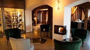 Un interior moderno con una cava de vinos, sillones tapizados en verde, una chimenea y una zona de estar acogedora.