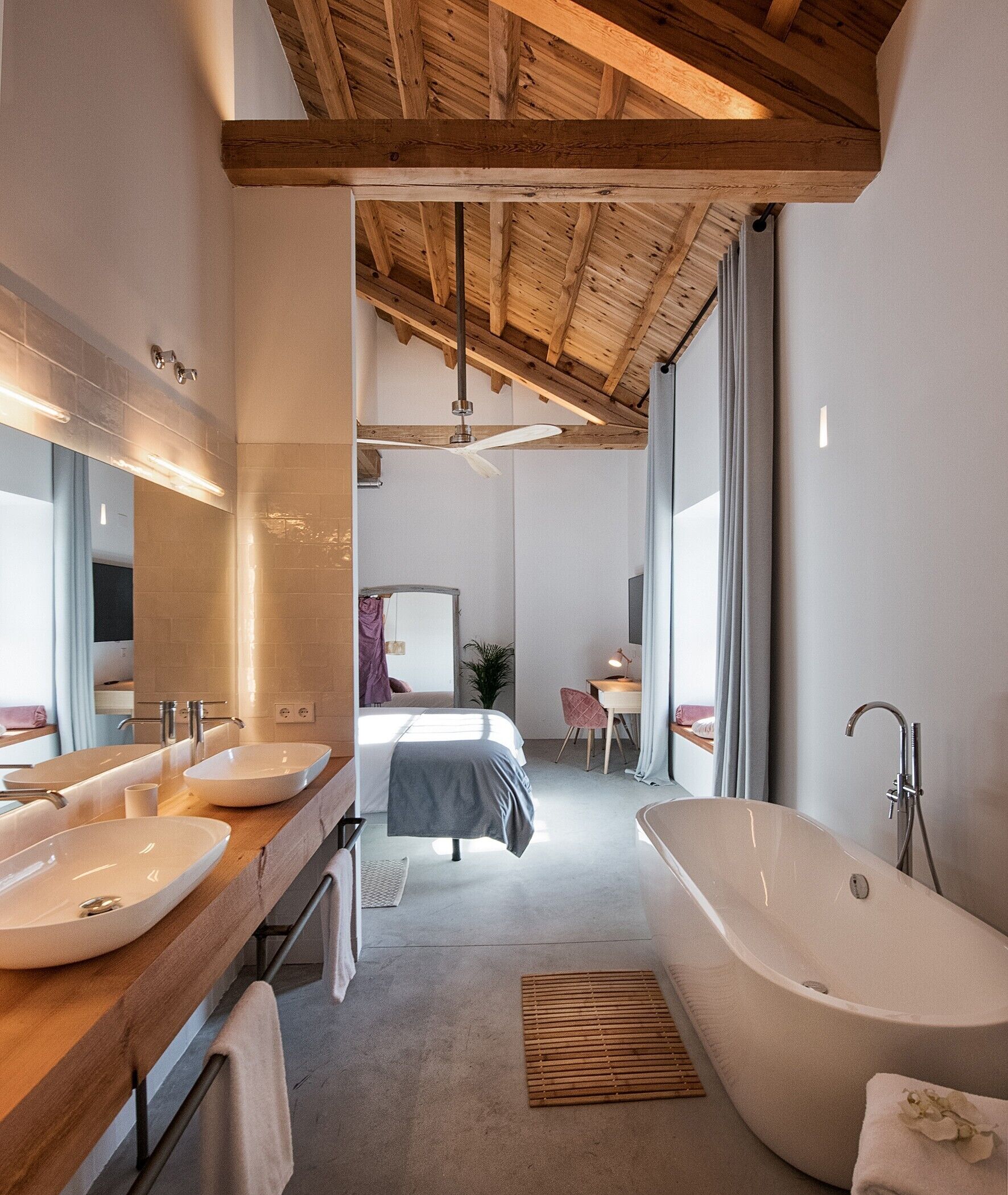 A modern bathroom with a large bathtub, two sinks, and a mirror.