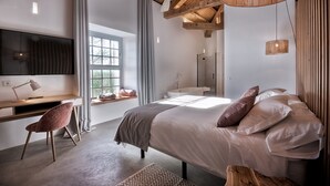 Un dormitorio moderno con cama, escritorio, silla, televisor y zona de ducha.