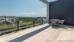 A balcony with a view of a residential area and a body of water. - Ocean View • Private Terrace • Luxury Rooftop & 1 Min to Beach (Playa del Carmen)