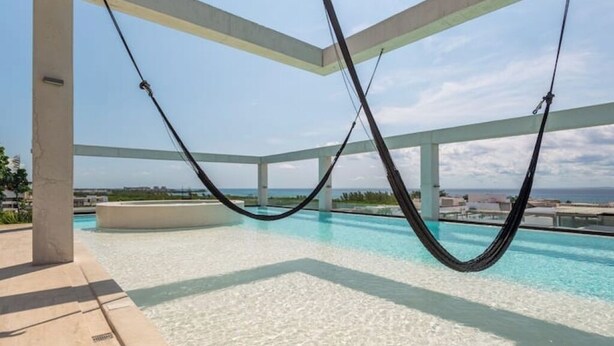 A pool area with a hammock and a view of the ocean. - Ocean View • Private Terrace • Luxury Rooftop & 1 Min to Beach (Playa del Carmen)