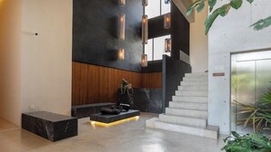 A modern lobby with a marble reception desk, a staircase, and a minimalist design. - Ocean View • Private Terrace • Luxury Rooftop & 1 Min to Beach (Playa del Carmen)