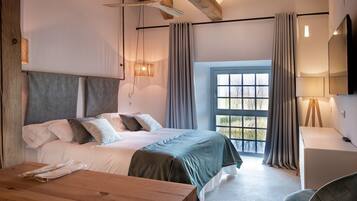 Ein Schlafzimmer mit Bett, Schreibtisch, Stuhl, einem Fenster mit Vorhängen und Deckenventilator.