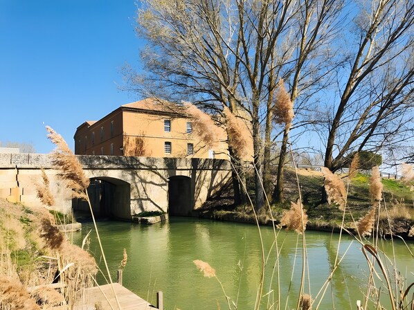 Un edificio con un puente sobre un río, rodeado de árboles y vegetación.