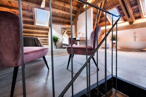 A room with a wooden ceiling, a bathtub, and two pink chairs. - Luxury Suite Magia de las Estrellas in Palencia, with Wi-Fi (Abarca de Campos)