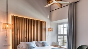 Un dormitorio moderno con una cama grande, un panel de madera con listones, una lámpara colgante y vistas al exterior.