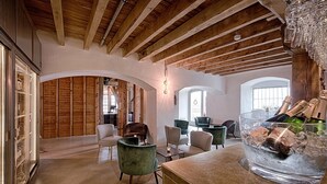 Amplia habitación con vigas de madera, un enfriador de vidrio para vino y varias zonas de estar.