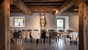 Un espace repas agrémenté de poutres en bois, d’une échelle ornée de plantes et de chaises recouvertes de fourrure.