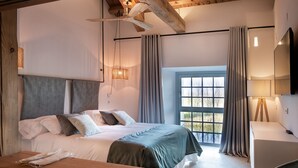 Une chambre à coucher comprenant un lit, un bureau, une chaise, une fenêtre avec des rideaux et un ventilateur de plafond.
