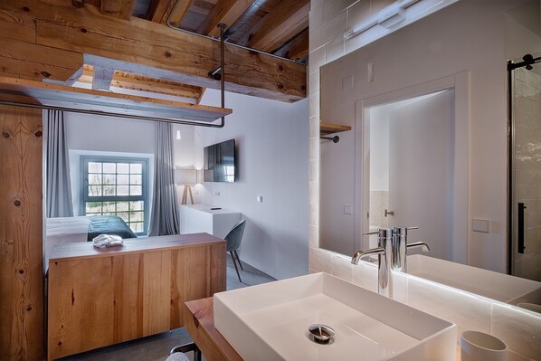 Un baño moderno con un lavamanos grande de color blanco, un espejo y una zona de ducha.