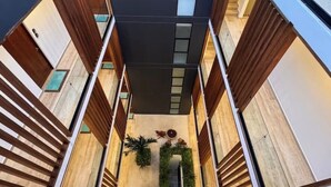 Ein modernes Gebäude mit einem zentralen Atrium, Holzlamellen und einer Grünpflanzenanordnung.
