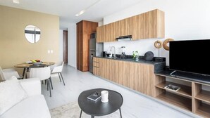 Eine moderne Küche mit Holzausstattung, einer schwarzen Arbeitsplatte und einem großen Flachbildfernseher.