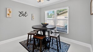 A dining area with a round table, six chairs, a ceiling fan, and a window with a view of the outside. - Work, Play or Recharge:3BR Pool Home near Legoland (Winter Haven)