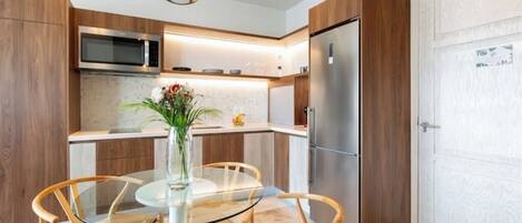 Una cocina moderna con armarios de madera, electrodomésticos de acero inoxidable y una mesa de comedor de vidrio con sillas de mimbre.