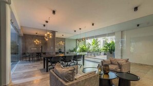 Un intérieur moderne comprenant un coin repas, des sièges et un mur de verre donnant sur un espace verdoyant.
